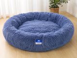 un panier bleu pour chien posé sur un parquet, à côté d'une plante en pot