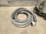 a hose and a vacuum on the floor next to a wall