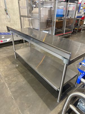 une grande table en acier inoxydable au milieu d'un entrepôt