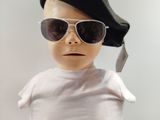 a baby wearing sunglasses and a hat with a cell phone in his mouth