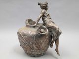 statue of a woman sitting on a vase with a bowl in her hand