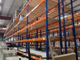 des rayonnages dans un entrepôt, sur lesquels sont posées des palettes et des cartons