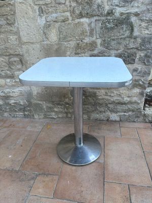 a small table with a blue top sitting on a brick floor