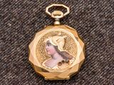 une montre de poche de couleur dorée sur laquelle figure le portrait d'une femme