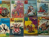 several books of comics are lined up on a white surface