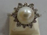 a pearl and diamond ring sitting on top of a marble block