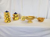 a lot of yellow vases on a table with a white table cloth