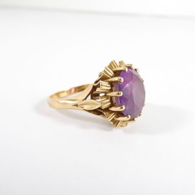 gros plan d'une bague en or avec une pierre violette