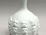 a white vase that has a bunch of flowers on it