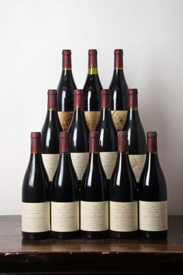 Des bouteilles de vin rouge sont posées sur une table devant un mur blanc.