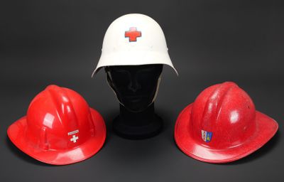 deux casques de chantier rouges et un casque de chantier blanc sur fond noir