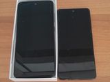 an open box with a black phone inside of it on a wooden surface