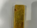 a gold bar sitting on a table next to a bottle of wine