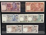 Quatre billets de banque différents sont exposés dans une vitrine.
