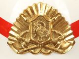 a gold plate with a rooster on it and a red ribbon
