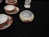 several cups and saucers sitting on a table with a statue in the background