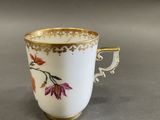 une tasse blanche avec un bord doré et un motif floral