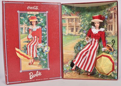 une poupée vêtue d'une robe à rayures rouges et blanches et d'un chapeau, dans une boîte rouge et blanche sur laquelle figure l'image d'une femme vêtue d'une robe à rayures rouges et blanches