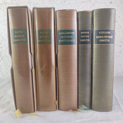 four old books are lined up on a white surface
