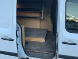 une camionnette blanche dont la porte est ouverte, garée sur le bord de la route