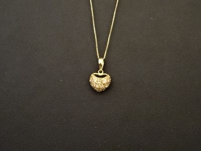 un collier plaqué or avec un pendentif en forme de pomme sur fond noir