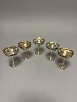 six verres à vin argentés posés sur des socles, disposés sur une table