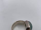 a close up of a ring with a green stone on a white surface