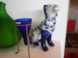 une statue de chien bleue et blanche posée sur une étagère à côté d'un vase vert