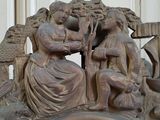 a clock with a statue of a woman and a man sitting on a bench