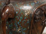 a bronze vase with an elephant on it on a table