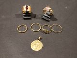 trois bagues en or et une pièce d'or posées sur une table