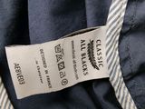 the label on the back of a blue jacket with a striped tie