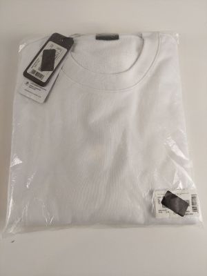 Le t-shirt blanc est emballé dans du plastique et porte une étiquette.