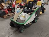 a lawn mower parked in a garage with other lawn mowers in the background