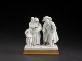 a white figurine of three people standing on a wooden base