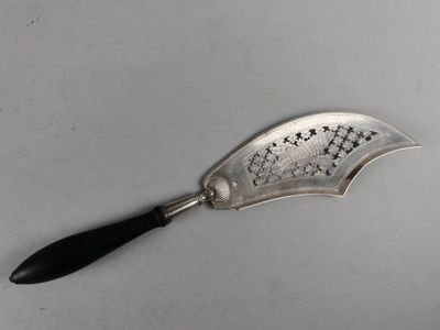 an old silver spoon with a black handle on a white surface