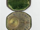 une boîte ouverte contenant une horloge, posée sur une surface blanche