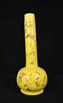 un vase jaune posé sur une surface noire