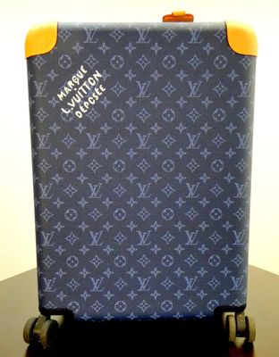 a blue suitcase sitting on a table with a yellow handle