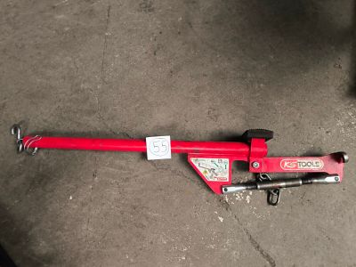 a red pipe cutter laying on the ground next to a black chair