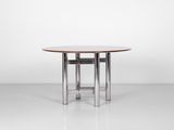 une table à manger ronde avec des pieds chromés et un plateau en bois