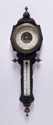 une horloge accrochée au mur, à laquelle est fixé un baromètre