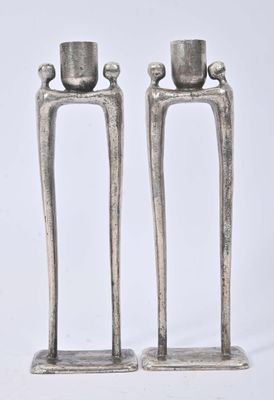 two silver candles that are sitting on a stand