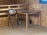 a small table and a chair in a room with plywood walls