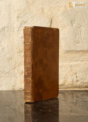 un vieux livre posé sur une table, avec un mur de pierre en arrière-plan