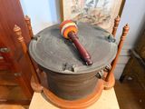 a wooden stand with a drum on top of it and a painting on the wall behind it