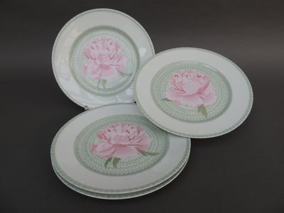 trois assiettes ornées de fleurs roses, posées sur une table