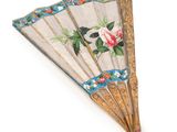 a close up of a fan with flowers on it on a white surface