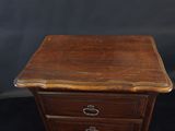 a close up of a small wooden table with drawers on it