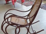 un fauteuil à bascule dans une pièce, avec une table en arrière-plan